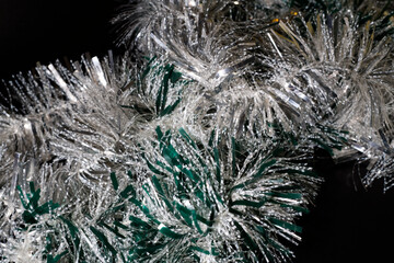 shiny christmas tinsel lies on a black background