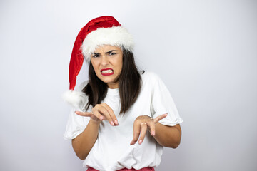 Young beautiful woman wearing a christmas hat over white background disgusted expression, displeased and fearful doing disgust face because aversion reaction. Annoying concept