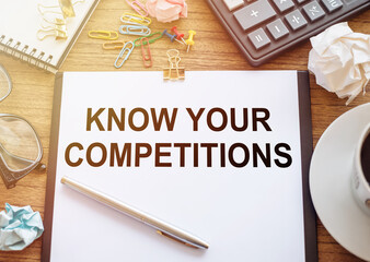 Office peper with KNOW YOUR COMPETITIONS text on wooden desk