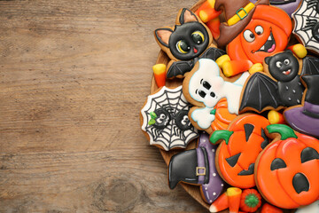 Fototapeta premium Tasty cookies and sweets for Halloween party on wooden table, top view. Space for text