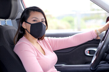 latin woman driver with protection mask in vehicle interior, new normal when driving