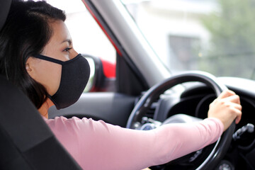 latin woman driver with protection mask in vehicle interior, new normal when driving