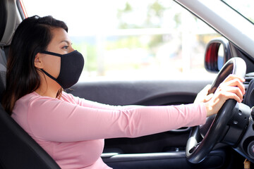 latin woman driver with protection mask in vehicle interior, new normal when driving