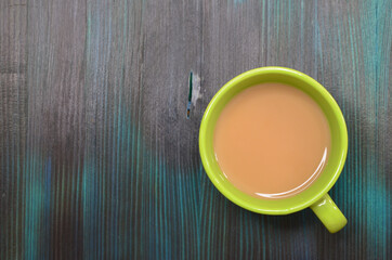 green ceramic mug with cocoa or coffee with milk top view on a wooden turquoise table