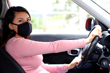 latin woman driver with protection mask in vehicle interior, new normal when driving