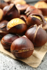Delicious roasted edible chestnuts on grey table, closeup