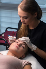 Beautician plucking eyebrows. Eyebrow care in a beauty salon.