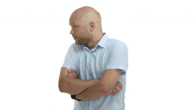Skeptical and disappointed bald male model with blue shirt, cross arms on chest and shaking head judgemental, dislike and disagree with something, standing over white background