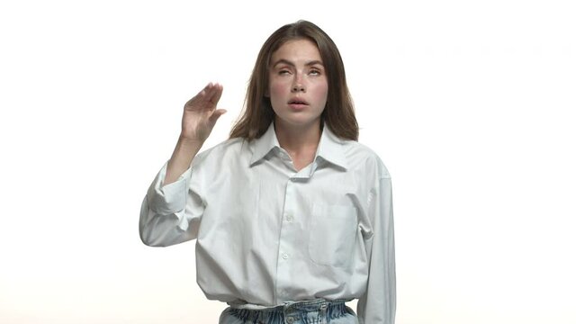 Video of attractive adult woman in white collar shirt looking bored, showing blah blah gesture, annoyed with empty talks, standing over studio background