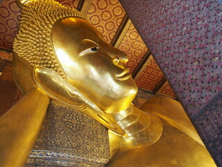 Close up of the Reclining Buddha gold statue's face, Wat Pho, Bangkok, Thailand