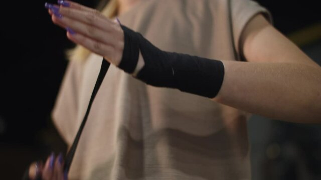Unrecognizable woman preparing for fight at gym. Closeup woman wrapping hands