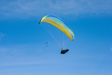Colourful paraglider on a blue sky background. Extreme sport. Crazy hobby.