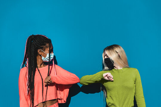 Young multiracial friends elbow greeting to avoid the spread of coronavirus instead of greeting with a hug - Social distance friendship greeting concept