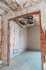 Extremely damaged wallpaper with collapsing ceiling, likely from water damage at an abandoned home in the Bannack ghost town of Montana