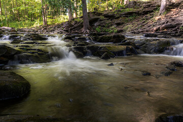 A long exposure shot of a small waterfall cascading down into a shallow pool of water in Hilton Falls near Toronto, Ontario.
