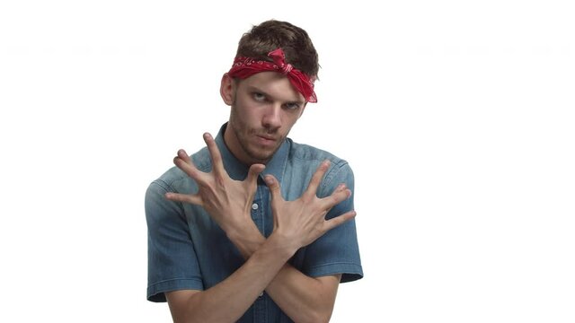 Video of handsome hipster with beard, wearing red headband and denim shirt, showing hiphop sign, west coast rap gesture, standing sassy over white background