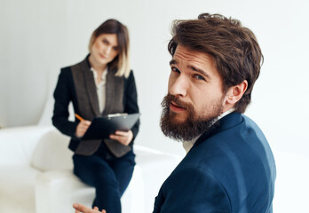 Business woman In a bright room and an upset man with a beard in the foreground is job interview