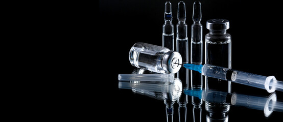 Medical syringe with a needle and a bollte with vaccine.