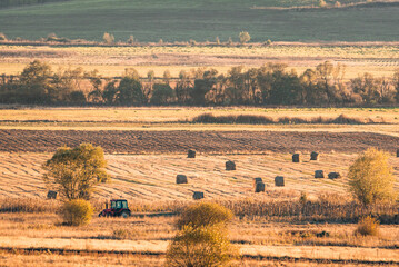 Lonely tractor harvest hay field crop stubble golden yellow orange autumn mountain background massive bulgaria technology machine agriculture