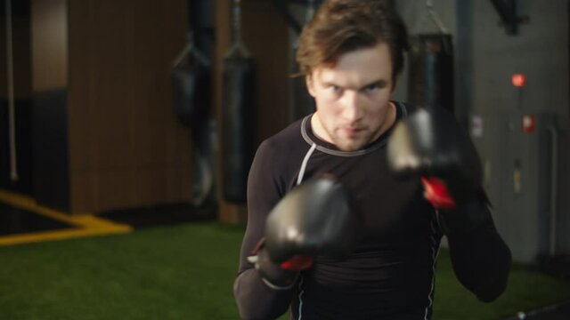 Wicked sport man practicing punches at gym. Athlete training in sport club