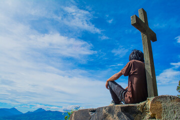 sentado bajo una cruz