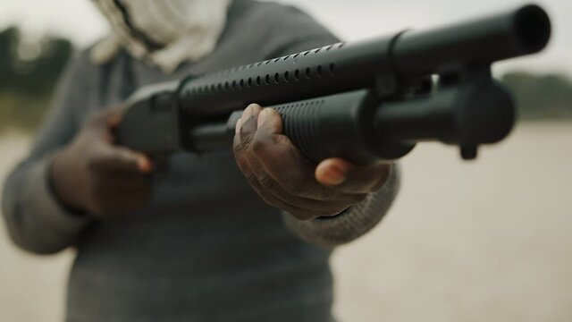 Afro-American man reloads pump action shotgun. Close up.