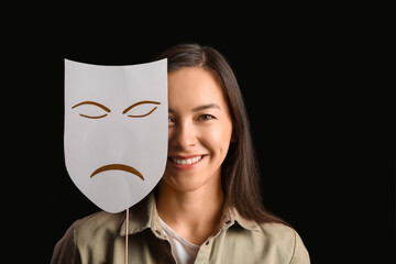 Happy actress with sad mask on dark background