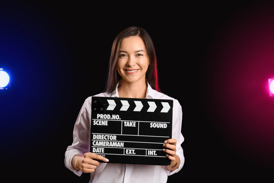 Young Female Film Director With Movie Clapper On Dark Background