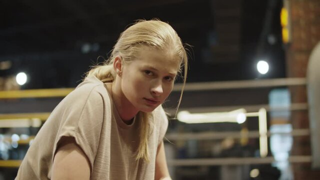 Sleepy female boxer having rest at gym. Fit girl making a pause on boxing ring