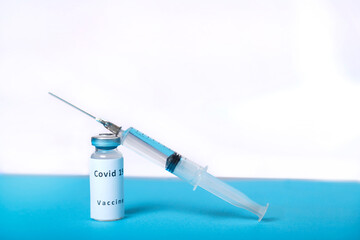 Virus vaccine and syringe on the table on a blue and white background.