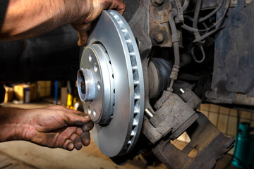 New brake disc with an anti-corrosion layer, mounted on the front hub, bolted by a mechanic.