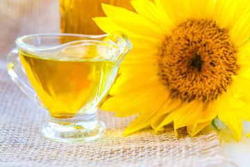 sunflower oil poured into glass saucepan. near flowers. on white background
