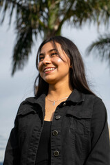 smiling woman with brackets on her teeth with a palm tree behind