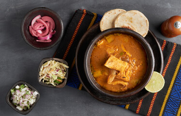 Traditional salvadoran beef feet and guts soup served with lemon, onion and corn tortillas, latin america food