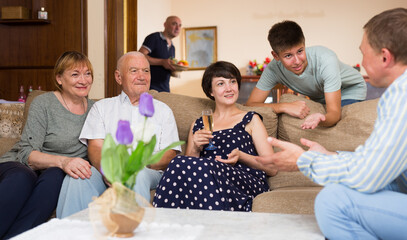 Big happy family gathering in parental home during family party, discussing pleasant topics