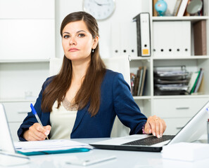 Smiling woman working with papers and laptop in office. High quality photo