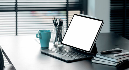 Fototapeta premium Mockup blank screen tablet with keyboard on black top table in modern office.