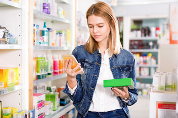 Smiling friendly girl reads a message on the phone in a pharmacy interior