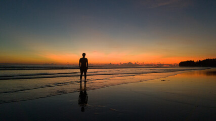 Fototapeta na wymiar young man standing on the beach at beautiful sunset