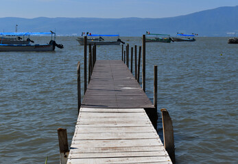 Fototapeta premium small boardwalk on Chapala lake and some boats in the back