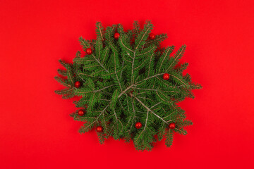 Top view of round Christmas background made with  fir branches and decorations over red background. Festive winter holidays background. Mock up.Copy space.