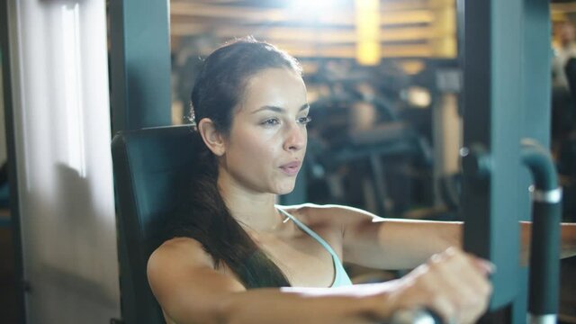 Attractive sport woman making bicep curls at gym. Fit girl doing workout in club