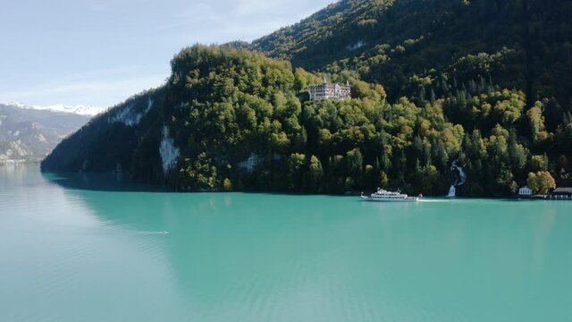 Ferry Boat Cruising On The Turquoise Blue Water Of Lake Brienz Near The Giessbach Waterfall In Brienz, Switzerland.  - aerial drone shot
