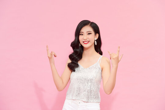 Female Posing In Long Silver Party Dress Over Pink Background