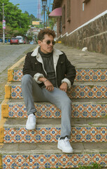 Male model in colorful colonial town. man dressed fashionably in aviator jacket and dark glasses