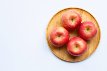 Juicy apples on wooden plate on white