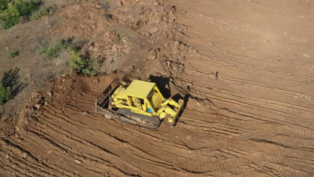 Earthworks Dozer (Bulldozer) Excavator in mountainous terrain, land correction and field clearing. 4K Aerial view