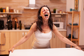 Terrified woman screaming after being brutally beaten by alcoholic husband. Violent aggressive husband abusing injuring terrified helpless, vulnerable, afraid, beaten and panicked wife.