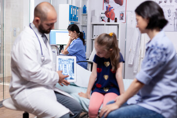 Doctor holding tablet with radiography during medical examination of child consultation. Healthcare...