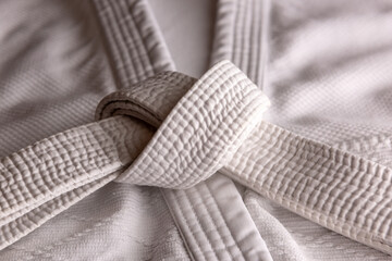 White judo, aikido, or karate belt, tied in a knot on white kimono